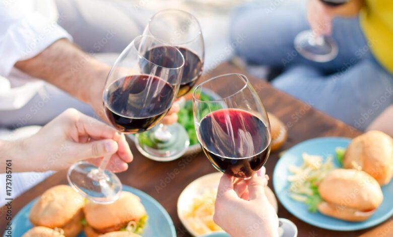 Hands Friends toasting red wine glass and having fun outdoors.