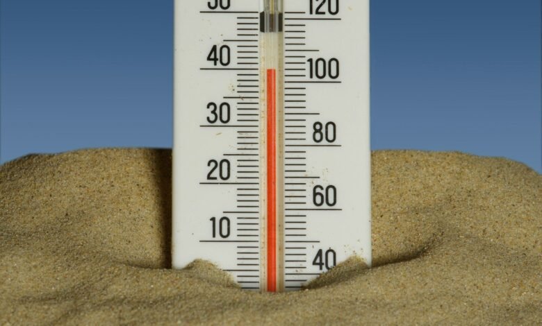A thermometer in the sand with a blue sky in the background