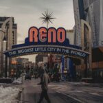 a man walking down a street under a neon sign
