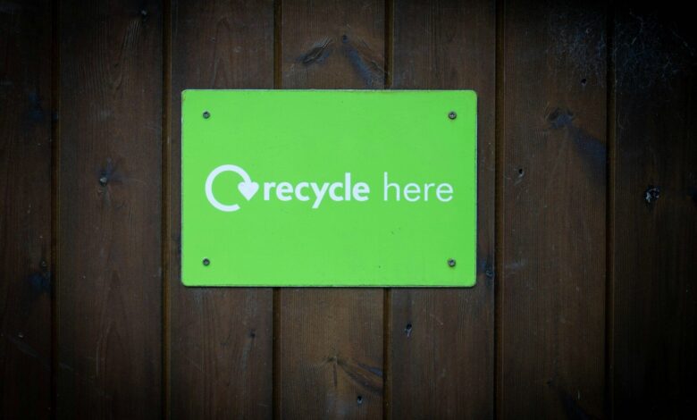 a green recycle here sign on a wooden wall