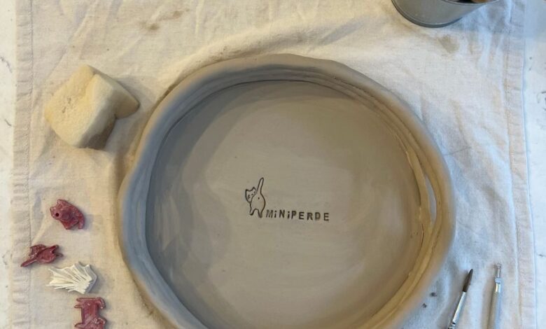 Beautiful clay bowl in progress with tools and materials on a pottery worktable.