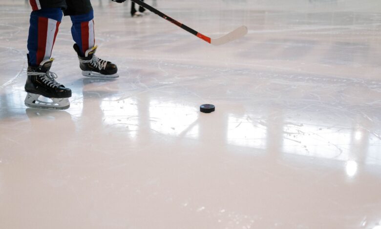 Dynamic shot of a hockey player maneuvering with stick and puck on ice rink.