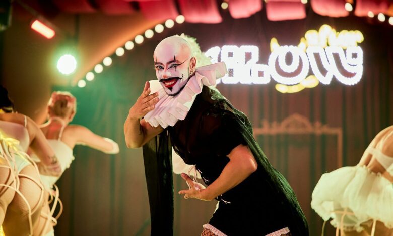 Performer in elaborate costume on stage with dancers